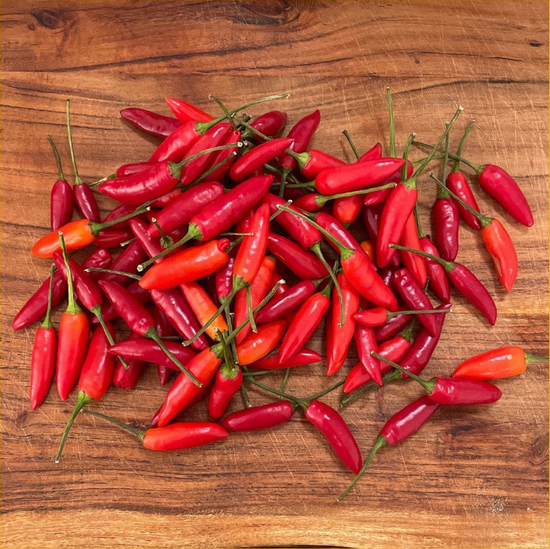 Fresh red chillis on a wooden chopping board. Each sauce uses fresh ingredience to perfect each sauce.  