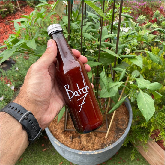 A man holding a chilli sauce that was made during the creation of burleigh chilli co. Each sauce went through multiple variations to nail the flavours the team was after.